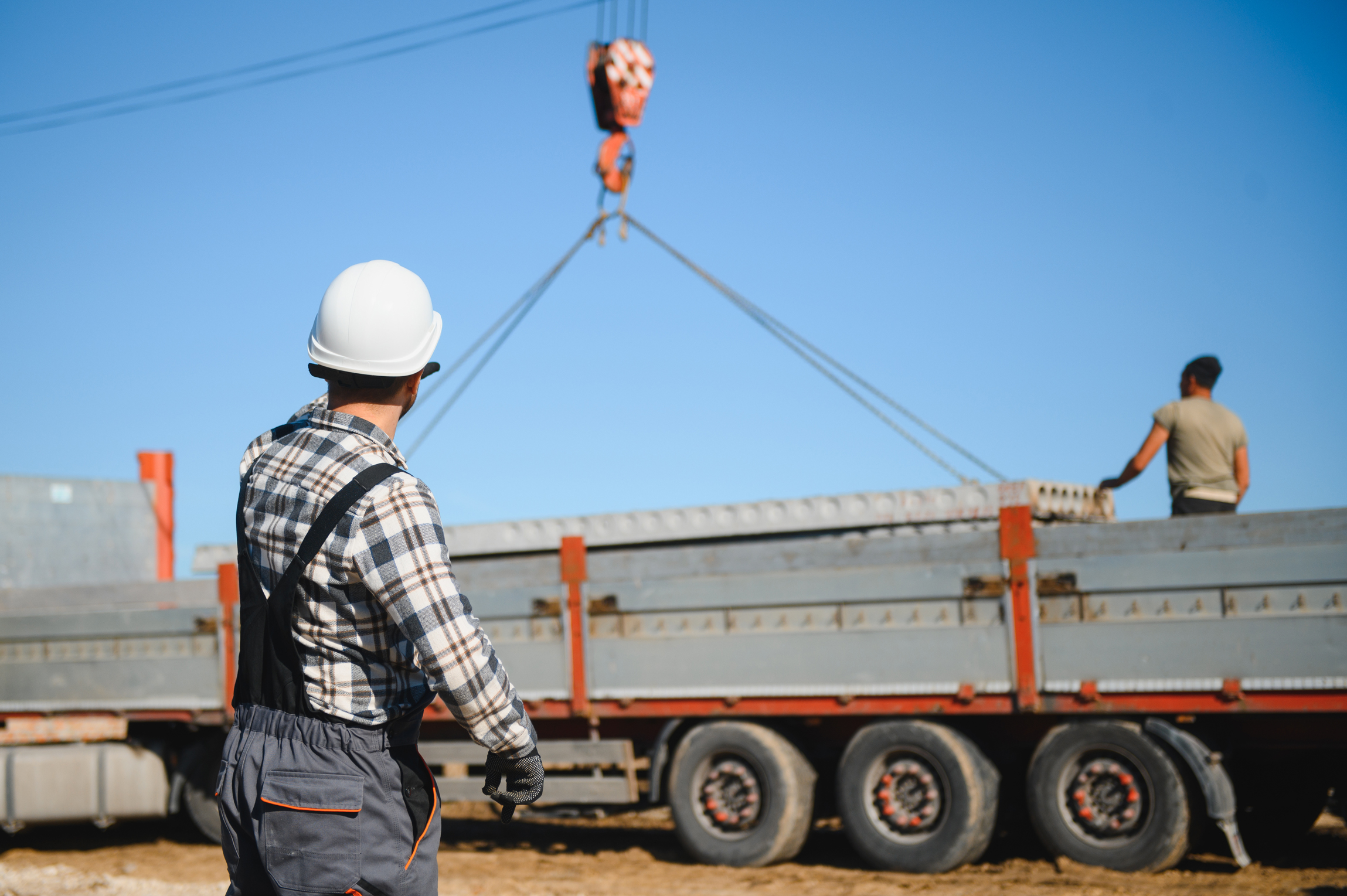 construction-worker-overseeing-crane-at-an-industr-2026-03-24-07-07-10-utc